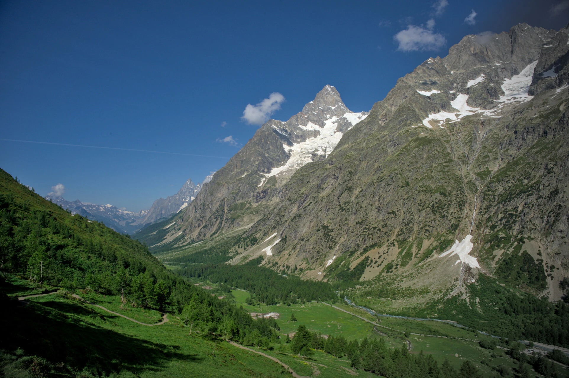 Morning meadows in the Italian Val Ferret, larch trees and snowy summits beyond